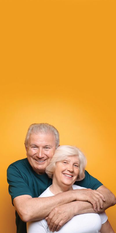 Un couple âgé heureux devant un fond orange